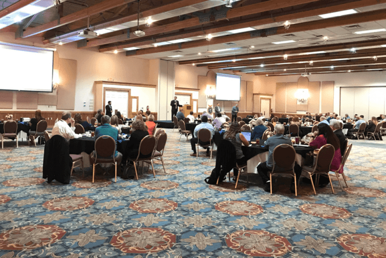 Group of People at Tables listening to speaker